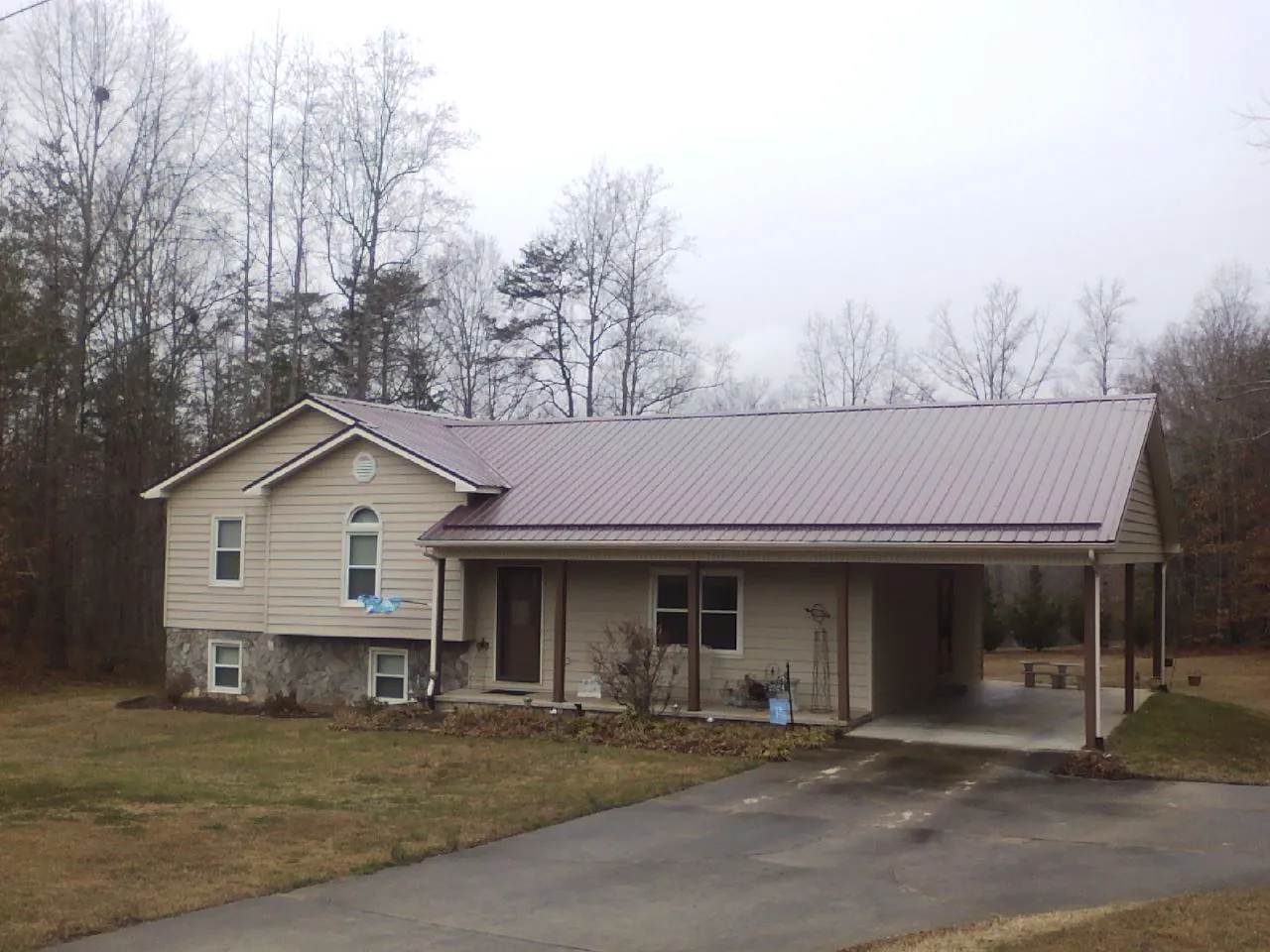 Burgundy metal roof on a tan split level home with an attached carport in Jewett