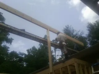 Carpenter setting a ridge beam over a new addition frame — Ice Dam Removal by Roofing Brothers in Jewett