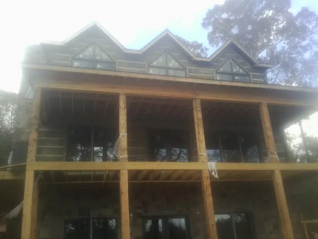 Dormers and porch framing on a large log home under construction — Roof Coating work by our crew in Jewett