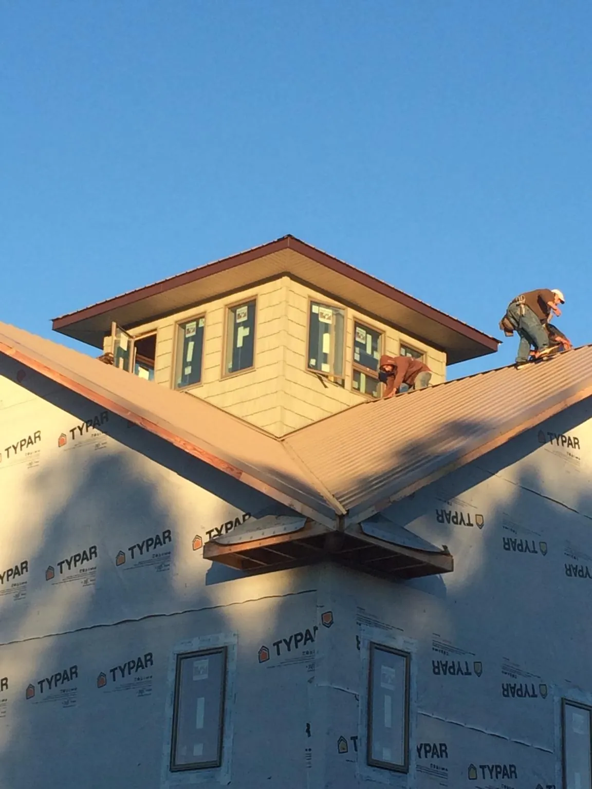 Roofers working around a rooftop cupola on a new metal roof at sunset — Roof Waterproofing in Jewett by Roofing Brothers